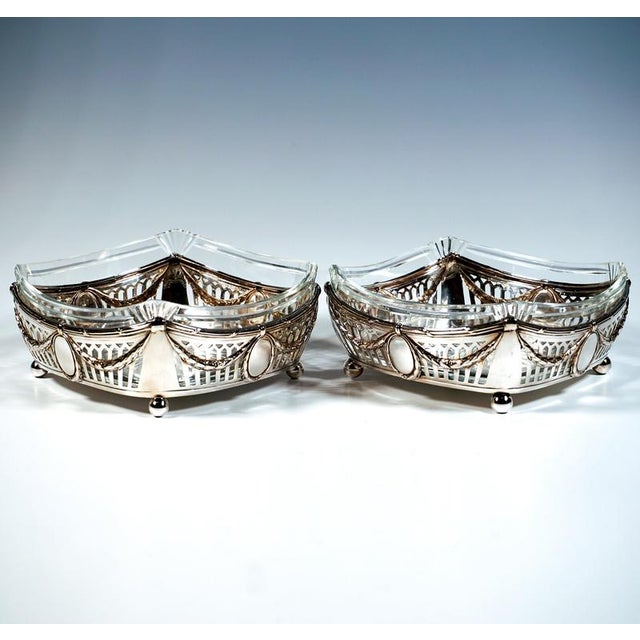 A pair of festive, elegant silver baskets with a square base, standing on four spherical feet; the sides gently curved...