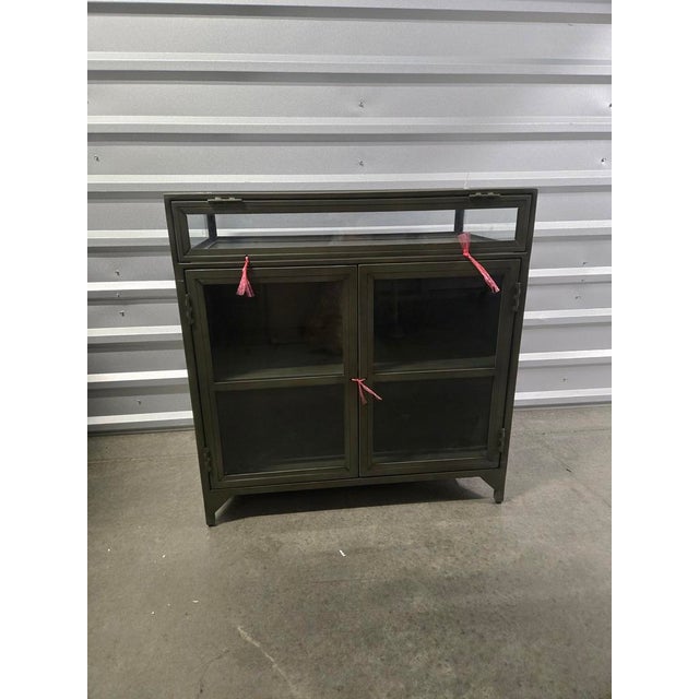 Low Industriial Style Curio Cabinet. Made from sleek gunmetal-finished iron, shadowbox-style cabinetry gives your inner...