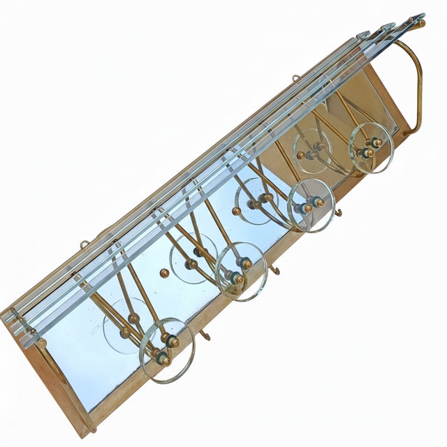Italian-made coat rack dating back to the 1950s, featuring a brass frame and details, a mirrored surface, and a glass-...