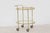 A French vintage brass cart from the 1950s with glass oval shelves and casters. Born during the mid-20th century, this...