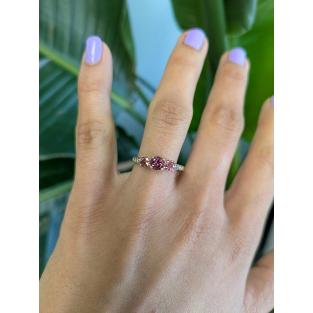 A rubellite tourmaline in a rich pink-red anchors this solid 14K yellow gold estate ring, flanked by two round pink...