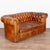 Pair of French Chesterfield two seat loveseat sofas upholstered in vintage brown leather. This handsome pair features...