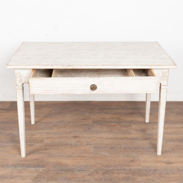 19th century Swedish desk or side table, crafted in pine. The table is raised on tapered legs topped by simple carved...