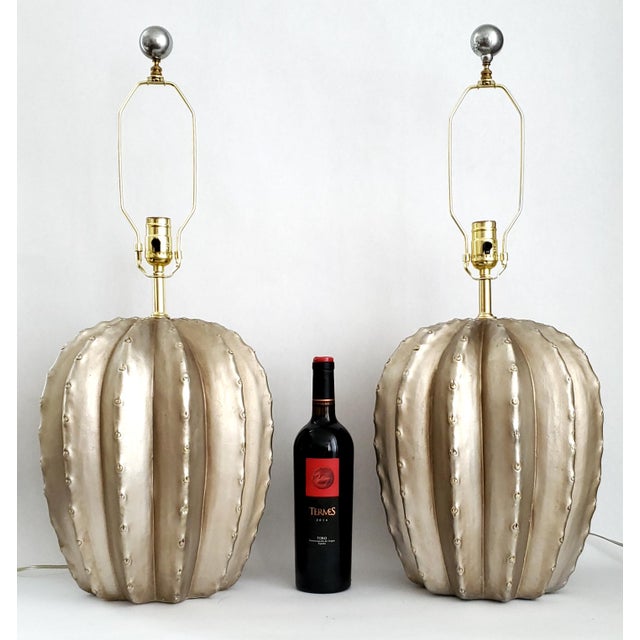 Offering a pair of metallic silver/platinum painted plaster cactus table lamps by Bon Art 1990. Both lamps are signed and...