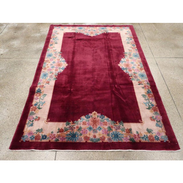 This mid-20th century Chinese Art Deco rug, features a striking composition with a deep burgundy field that exudes warmth...