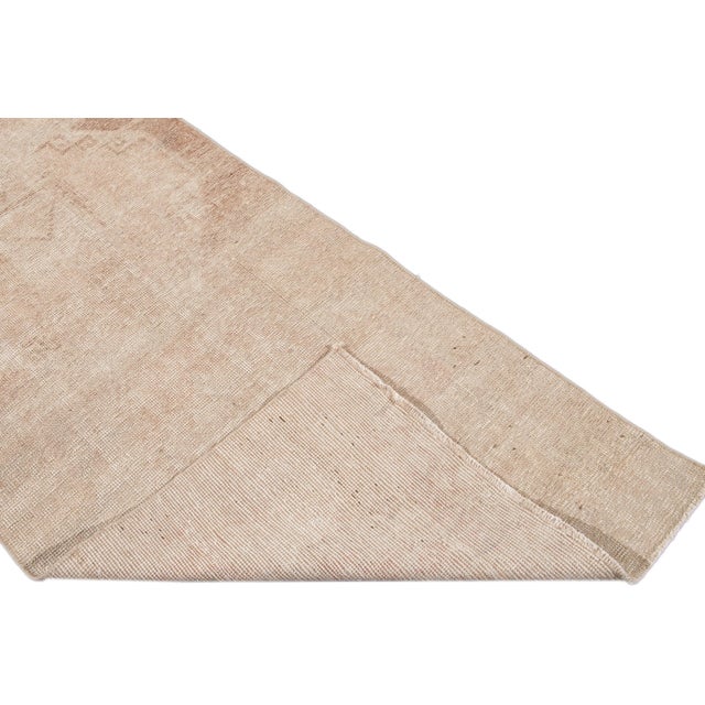 Beautiful vintage Turkish hand knotted wool rug with a tan field. This rug has beige accents in a gorgeous all-over...