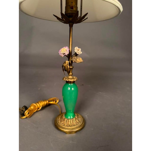 A charming early 20th-century French table lamp featuring an elegant combination of bronze, green glass, and hand-crafted...