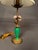 A charming early 20th-century French table lamp featuring an elegant combination of bronze, green glass, and hand-crafted...