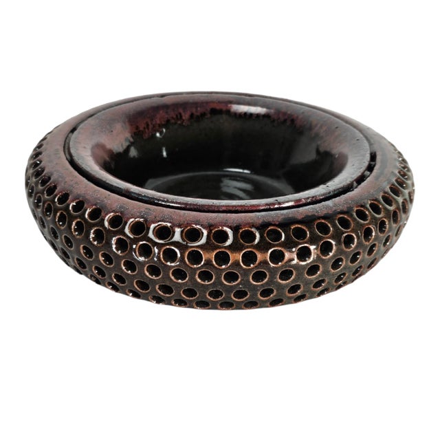 This is a vintage sculptural bowl in a rich brown iridescent glaze. It features a series of equidistant decorative holes...