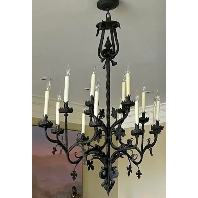 Large-scale mid-20th century hand-forged wrought iron chandelier featuring a twisted central stem with scrolling arms and...
