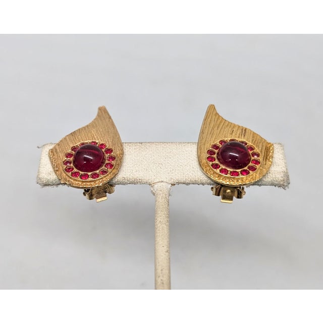 1950s or 1960s textured goldtone with a single cabochon faux-garnet surrounded by small round faux-garnets clip earrings....