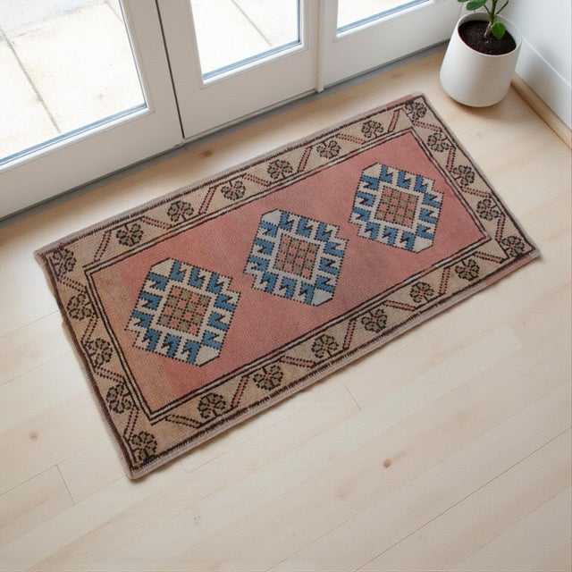 This charming petite rug features a beautifully sun-faded salmon peach background adorned with three striking blue and...