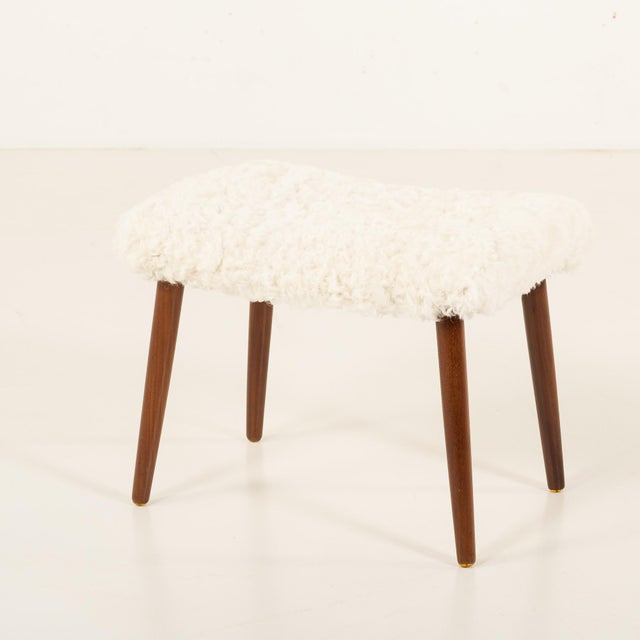 This Danish mid-century footstool was made in the late 1960s or early 1970s. It features solid wood legs and is newly...