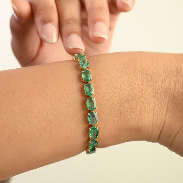 This elegant tennis bracelet features 23 oval cut emerald totaling 14.49 carat set in rich 14K yellow gold each emerald...