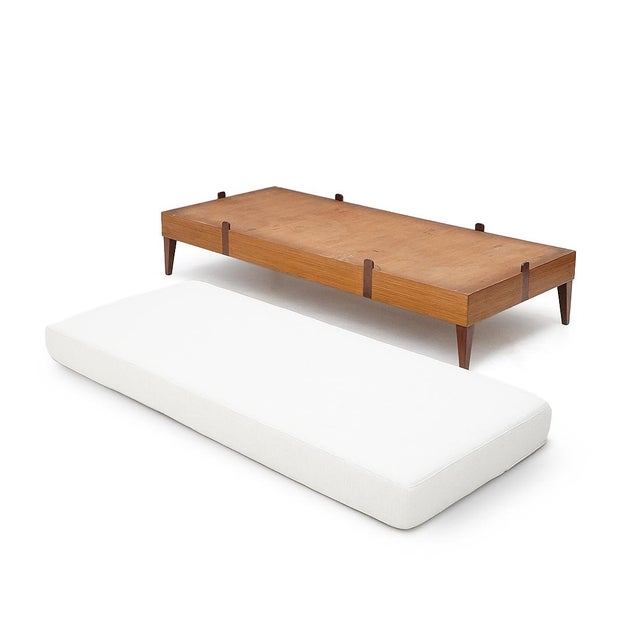 1950s daybed featuring a clean, essential silhouette and a structure crafted from solid wood and veneered wood, raised on...