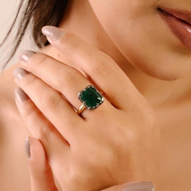 This handcrafted solitaire ring features a single large octagon-cut emerald weighing 4 carats, set in 18K yellow gold with...
