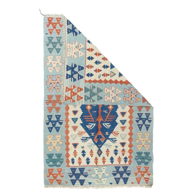This vintage to recent Anatolian pileless prayer rug presents an ecru-ivory field in which floats a denim blue pointed...
