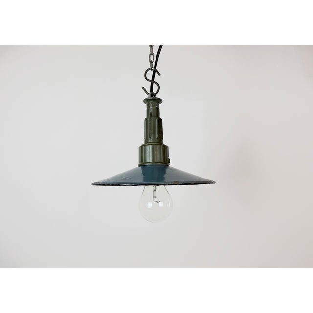 Industrial blue enamel pendant light made in Poland during the 1960s. White enamel inside the shade. Green cast aluminium...