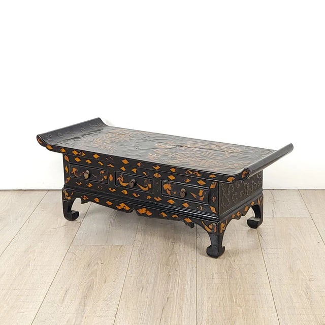 A Korean scholar's low table with three drawers and hoof feet, inlaid with a dragon, circa 1900. This piece has small...