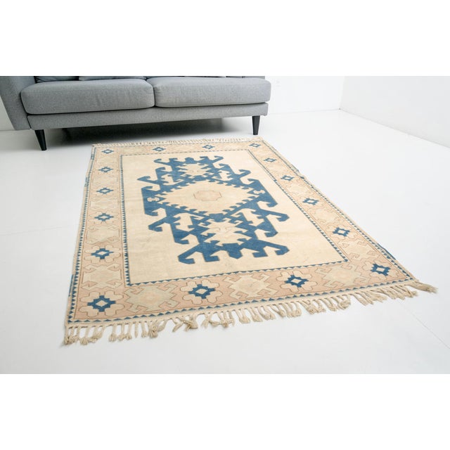 This is a vintage Turkish Oushak rug from the Mid 20th Century. The piece was hand-knotted.