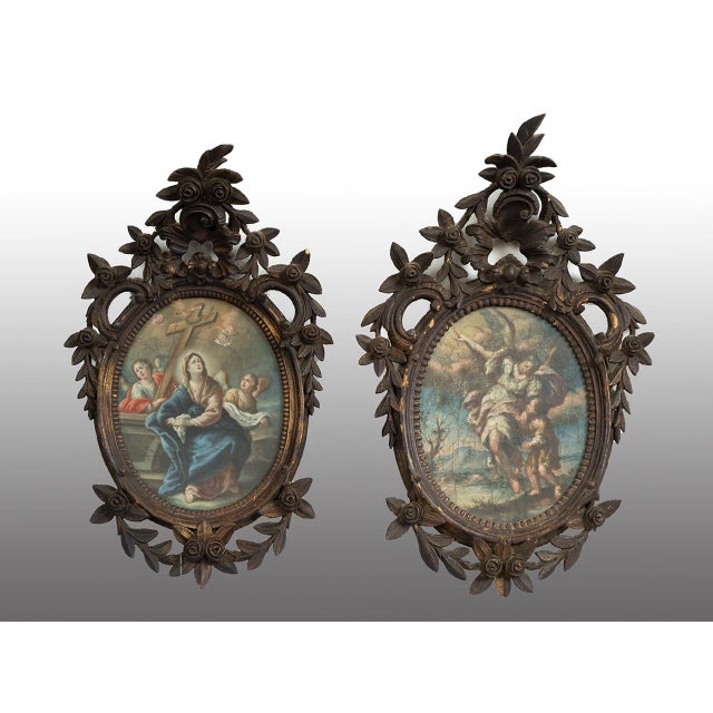A pair of antique oil-on-canvas paintings depicting religious scenes in period wooden frames. In one, the scene depicts...
