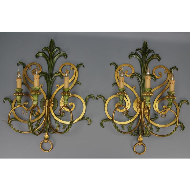 A pair of large gilt and green color metal and wood sconces, Italy, ca. the 1960s. This impressive pair of Baroque-style...