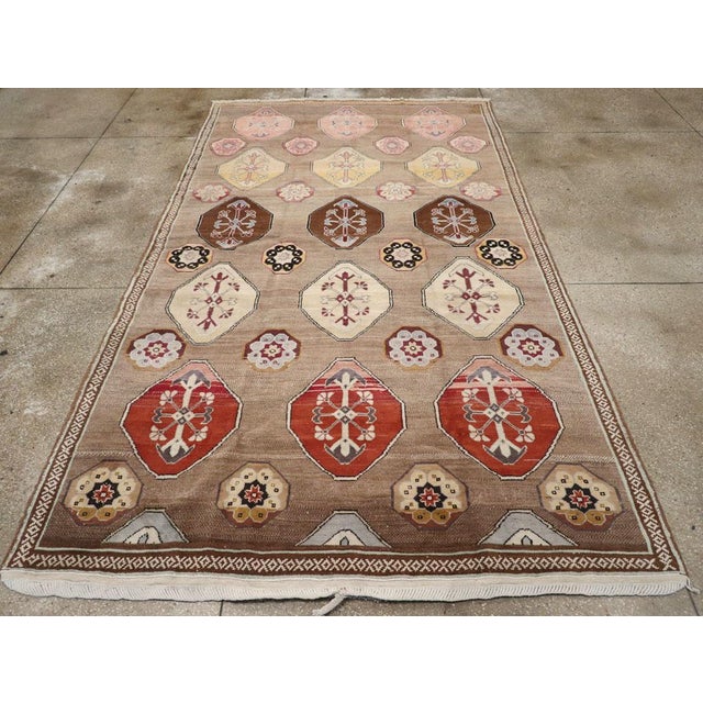 This mid-20th century Turkish Anatolian tribal room-size carpet, measuring 7' 2" x 12' 6", showcases a lively and rhythmic...