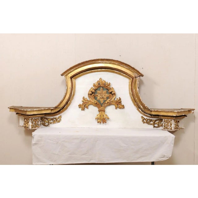 An Italian 18th century grand-scale gilded and painted wood pediment fragment. This antique architectural fragment from...