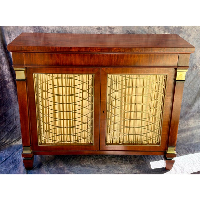 Elegant vintage credenza by Kittinger, crafted in richly figured mahogany with beautifully detailed brass grille doors and...