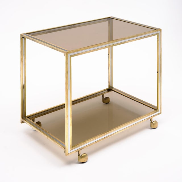 Modernist French bar cart made of brass and chrome by iconic Italian designer Romeo Rega. This piece has a top and bottom...