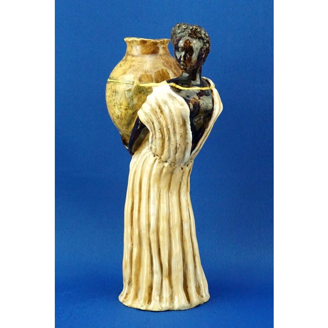 Majolica ceramic sculpture, entirely handcrafted without a mold, depicting an African woman with a vase, signed inside...
