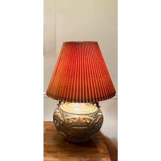 This captivating large lamp’s focal point is the deeply carved or molded relief figures with distinct faces and geometric...