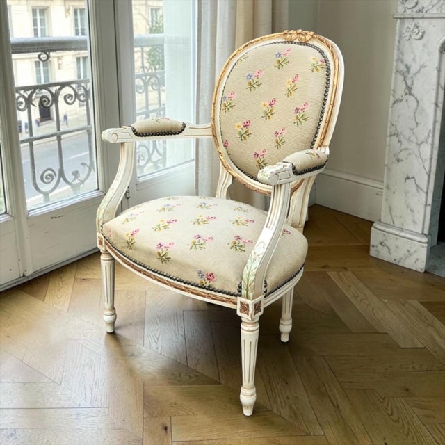 This 19th century French Louis XVI style armchair presents an elegant neoclassical form enriched with carved ornament, a...