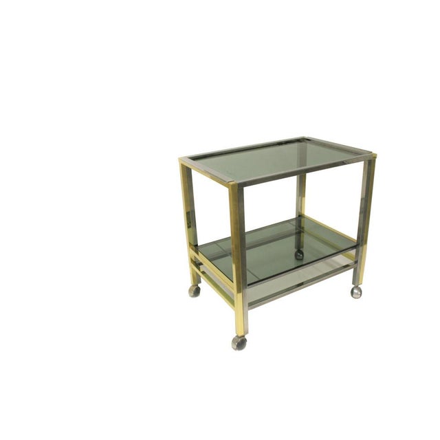 Brass and chrome two tier serving trolley. Made of smoked glass and a removable tray at the top. 1970s - Italy Dimensions:...