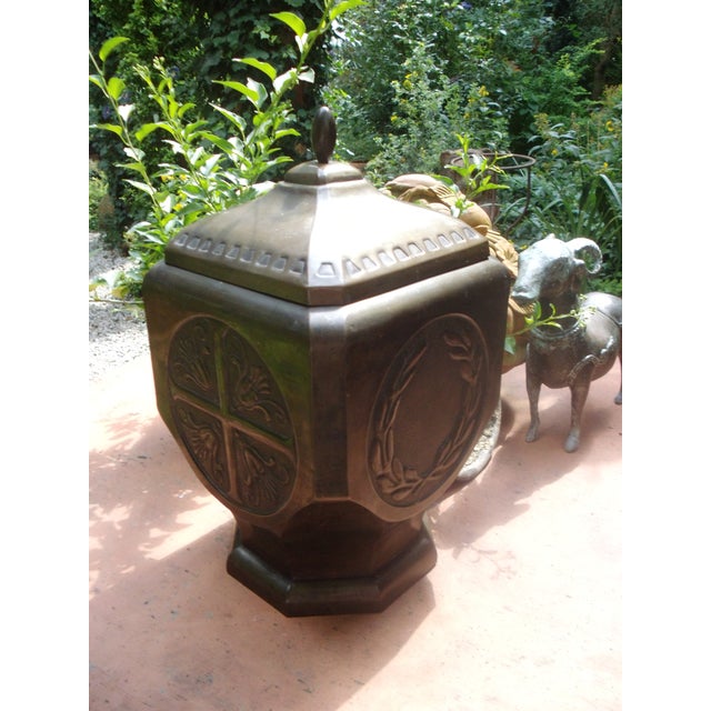 An antique, large lidded box made of brass sheet, with embossed laurel wreaths and another floral cross motif. An...