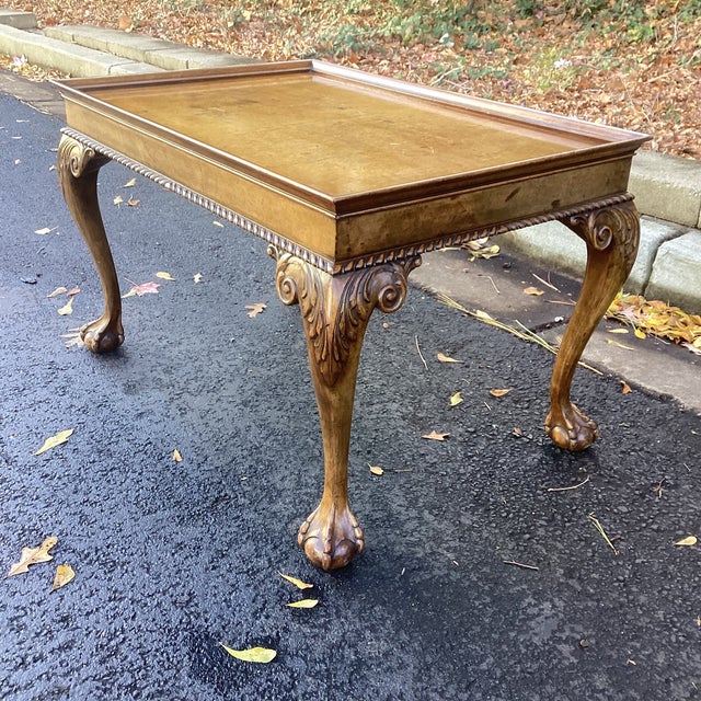 Elegant vintage coffee table featuring a richly patinated wood top framed by a raised gallery edge. The surface shows...