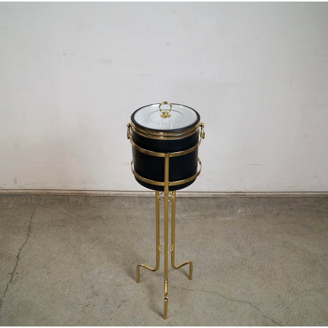 Vintage Hollywood Regency brass champagne ice bucket stand and ice bucket. It comes with a three-legged stand and an ice...