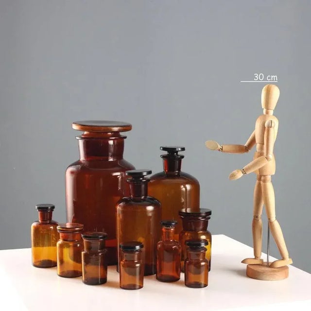 Set of 10 amber glass apothecary jars, of various sizes. This piece is attributed to the mentioned designer/maker. It has...