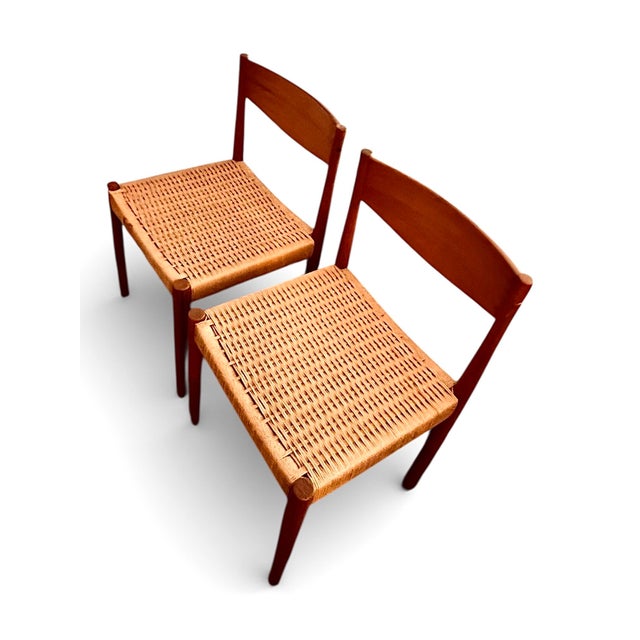 Elegant pair of mid-century modern dining chairs featuring sculpted teak-toned wood frames and beautifully executed woven...