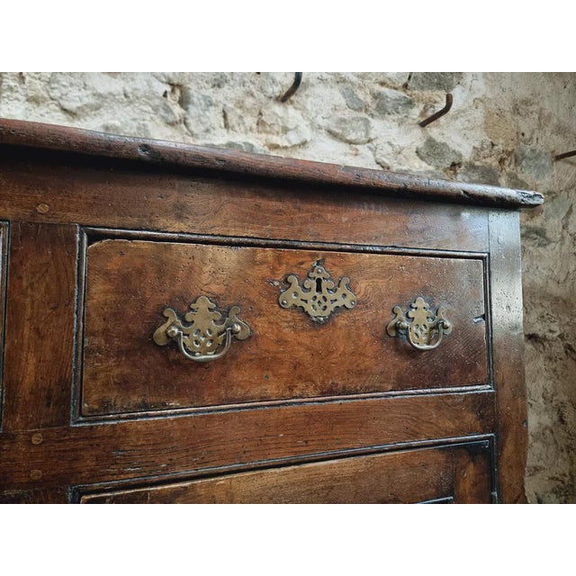 This 18th-century English sideboard is made of solid chestnut wood. It features three drawers and two doors with interior...
