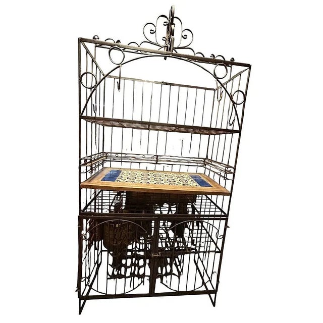Substantial freestanding wrought iron baker's rack or kitchen storage cabinet featuring an ornate architectural frame with...