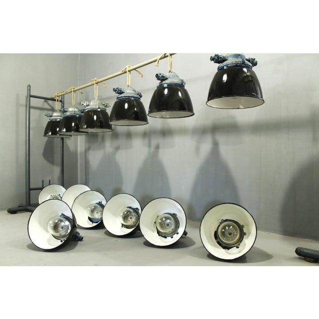 Industrial light fixtures in their original condition; the electrical system requires inspection; the enameled shades are...