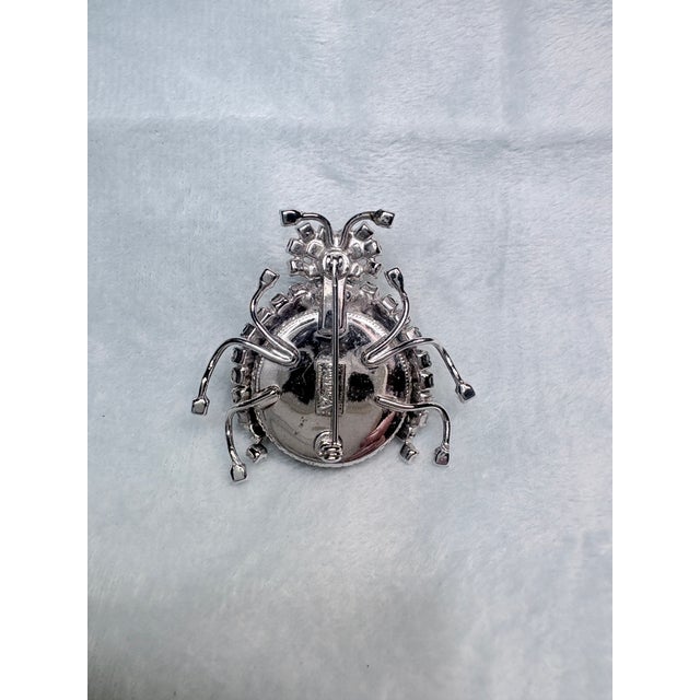 A striking signed Vendôme figural insect brooch featuring a dramatic ruby-red Lucite body framed by sparkling clear and...