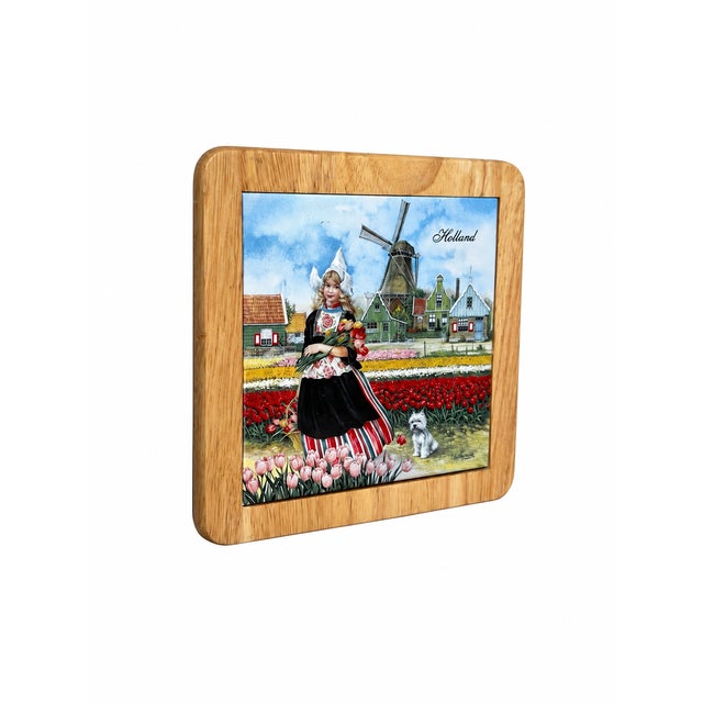 A charming Dutch-themed ceramic tile displayed in a warm natural wood frame with softly rounded corners. The colorful...