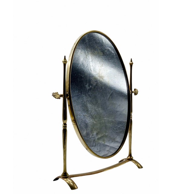 An elegant, vintage swivelling table mirror, crafted with a refined solid brass frame. Its slender silhouette is...