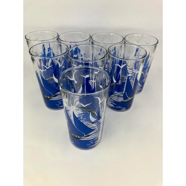 Set of 8 Vintage Tumblers in a Boat-Shaped Caddy. Glasses are decorated with blue sailboats in the ocean and white birds...