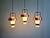 A trio of scandinavian pendant lights from the 1960s, each composed of a white opaline glass globe topped with a copper-...