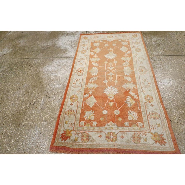 A vintage Turkish Oushak throw rug. The warm salmon – rust ground displays a spacious array of various types of palmettes,...