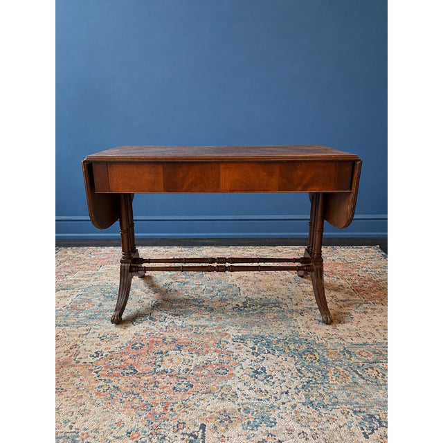 Attractive two-drawer sofa table with drop leaves featuring a double stretcher base, reeded outswept legs, and brass paw...