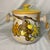 The set includes two pieces adorned with hand-painted grapes and leaves against a light background with yellow lids....
